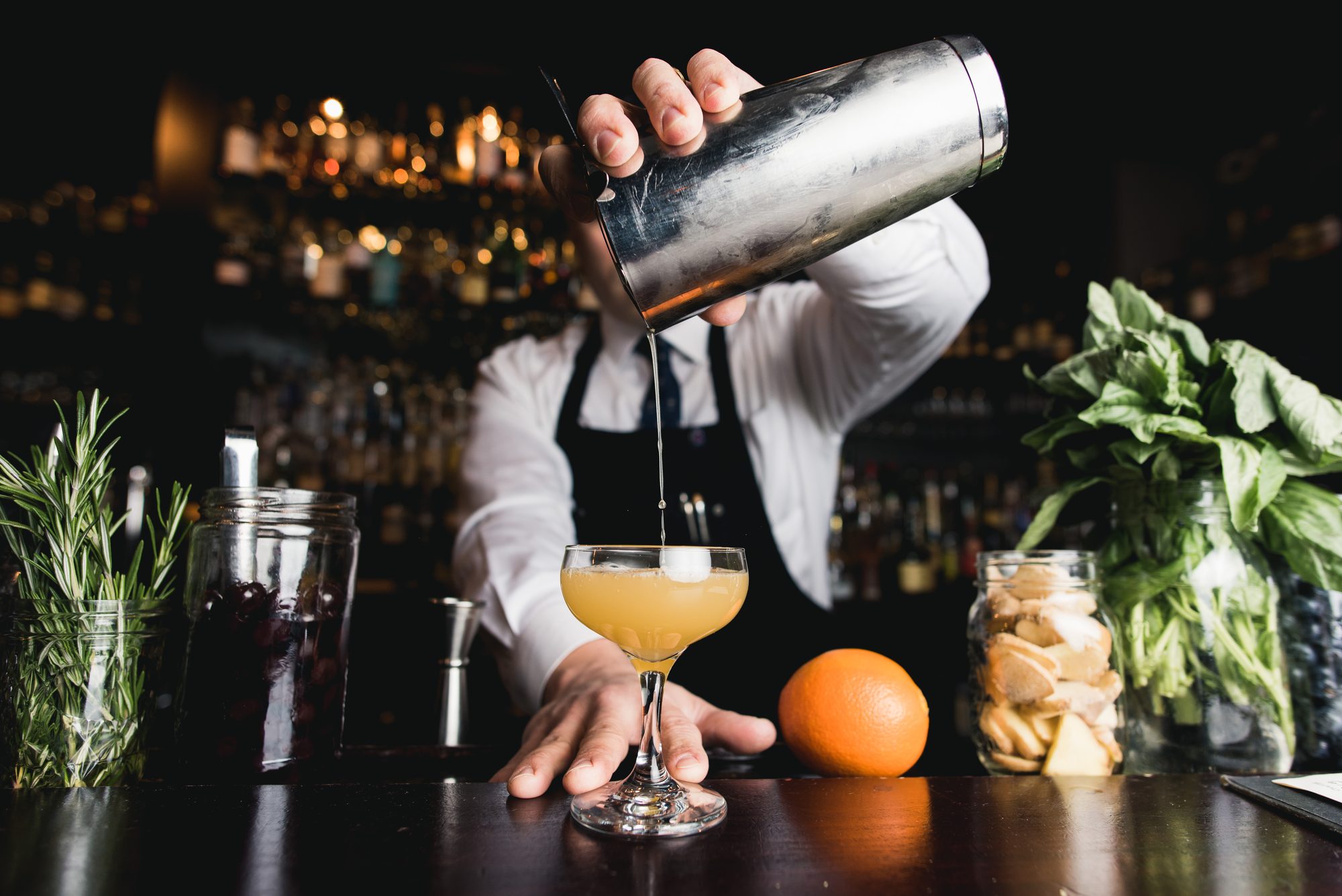 Service au shaker, botanicals frais sur le bar.
