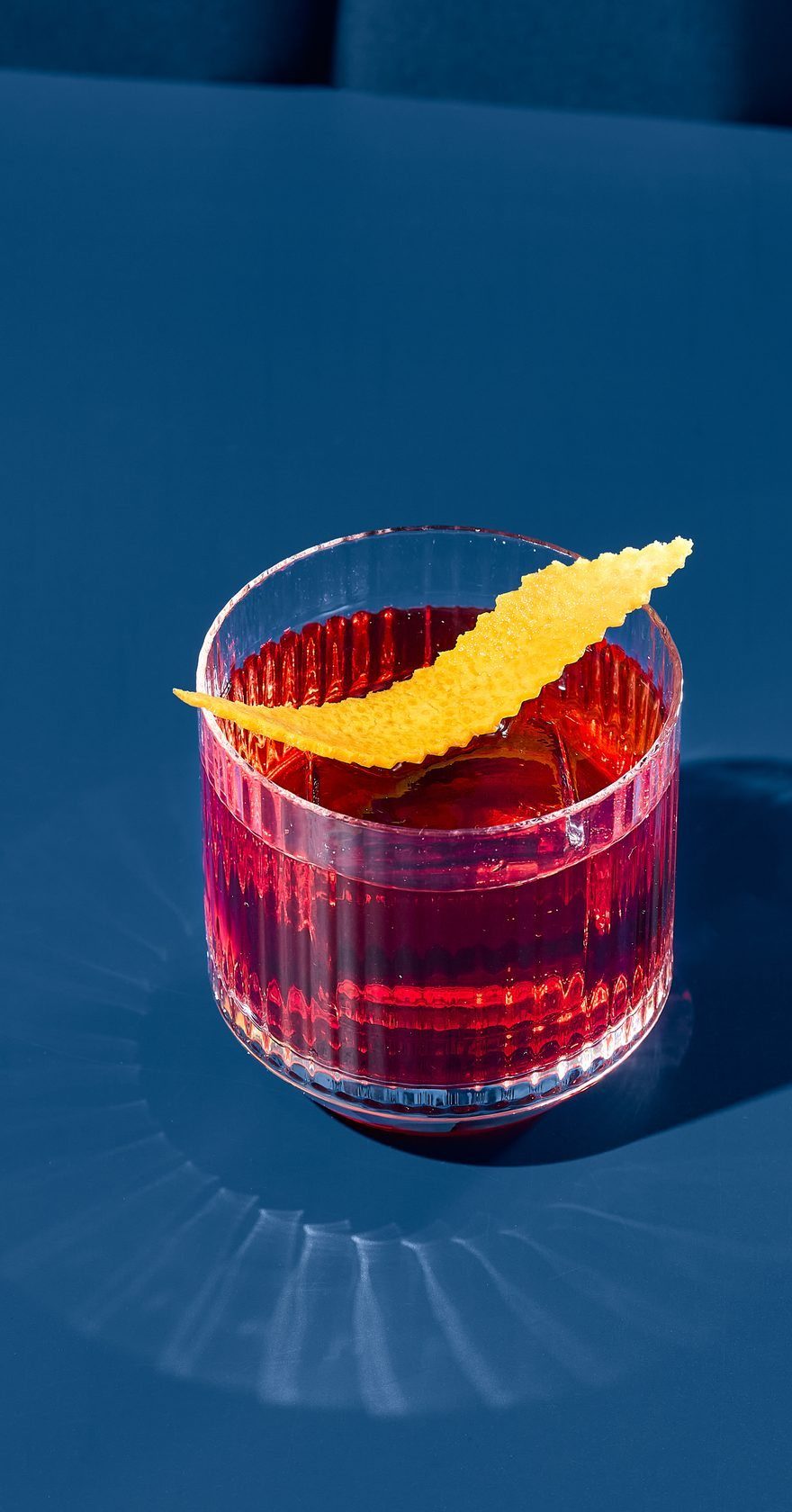 Verre rocks, mocktail rubis et zestes d'orange.